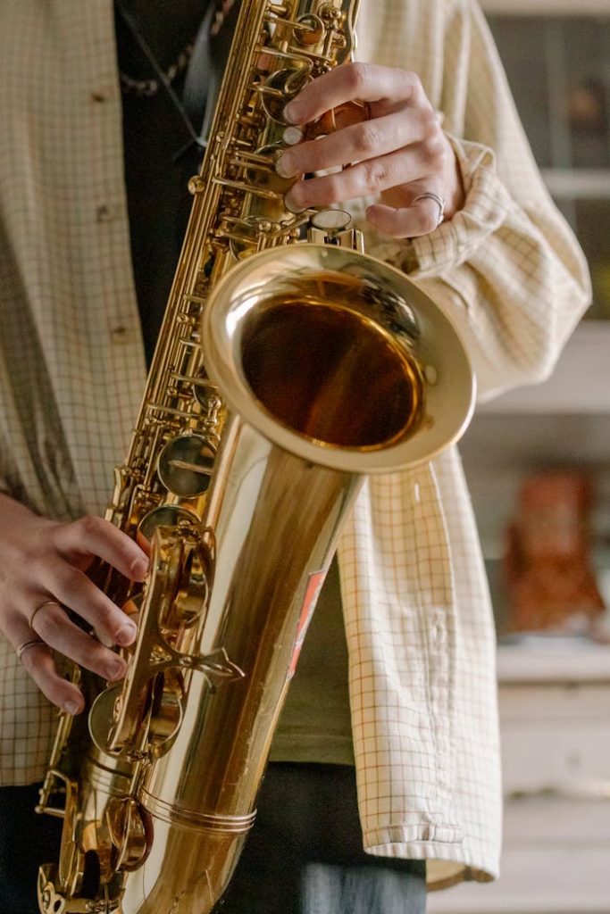 A detailed close-up of a musicians hands playing a saxophone in an indoor setting.