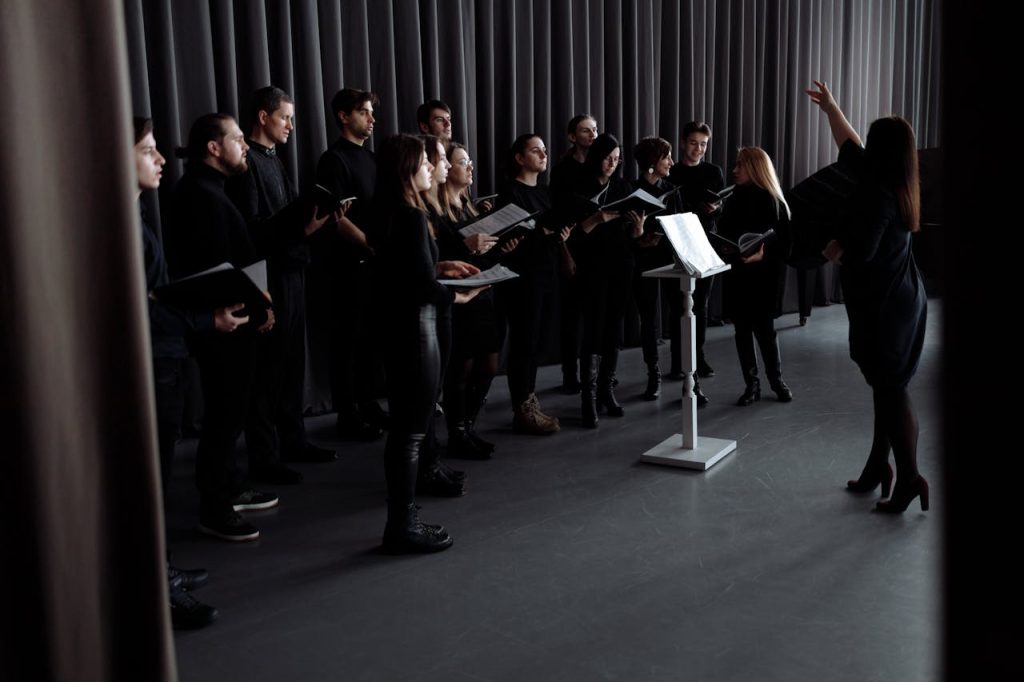 A choir practicing under a conductors guidance in an indoor studio setting.