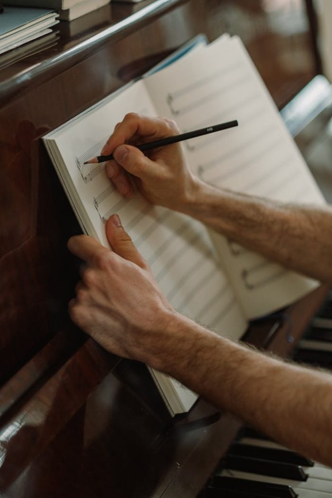 A person composing music with pencil and sheet on a piano. Captures artistic creativity.